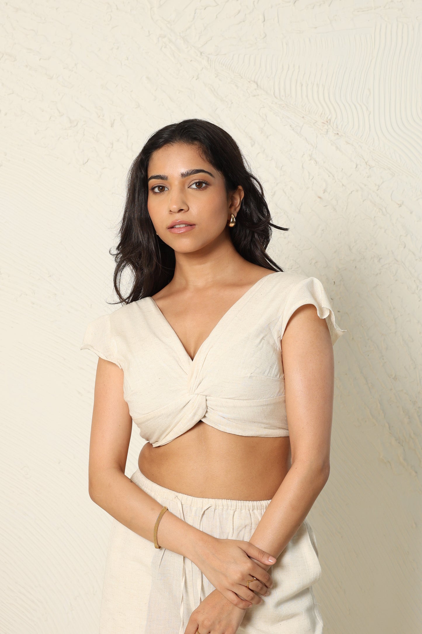 Woman wearing a beige top with a textured white background