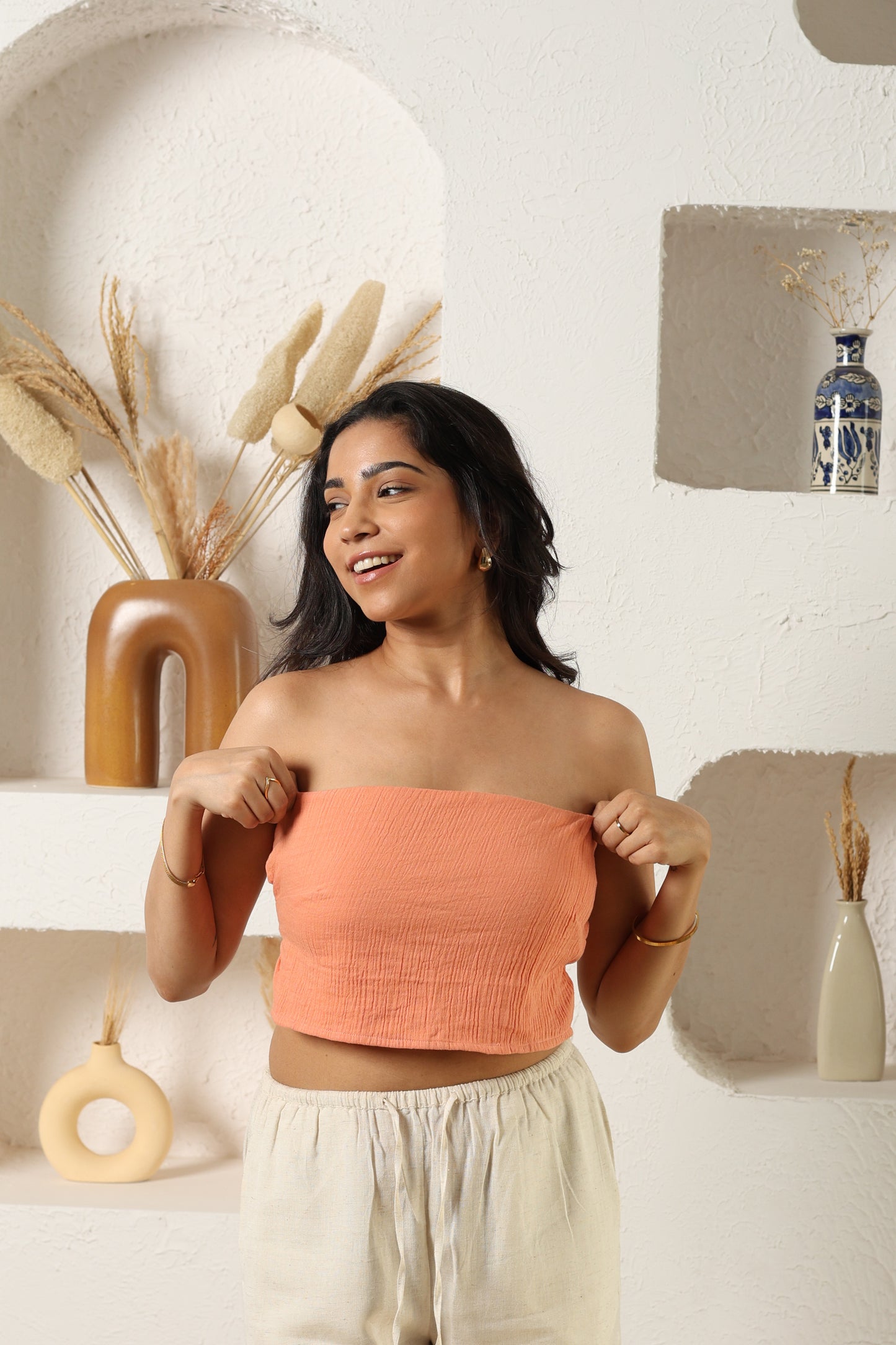 An orange top and white pants in a decorative indoor setting.
