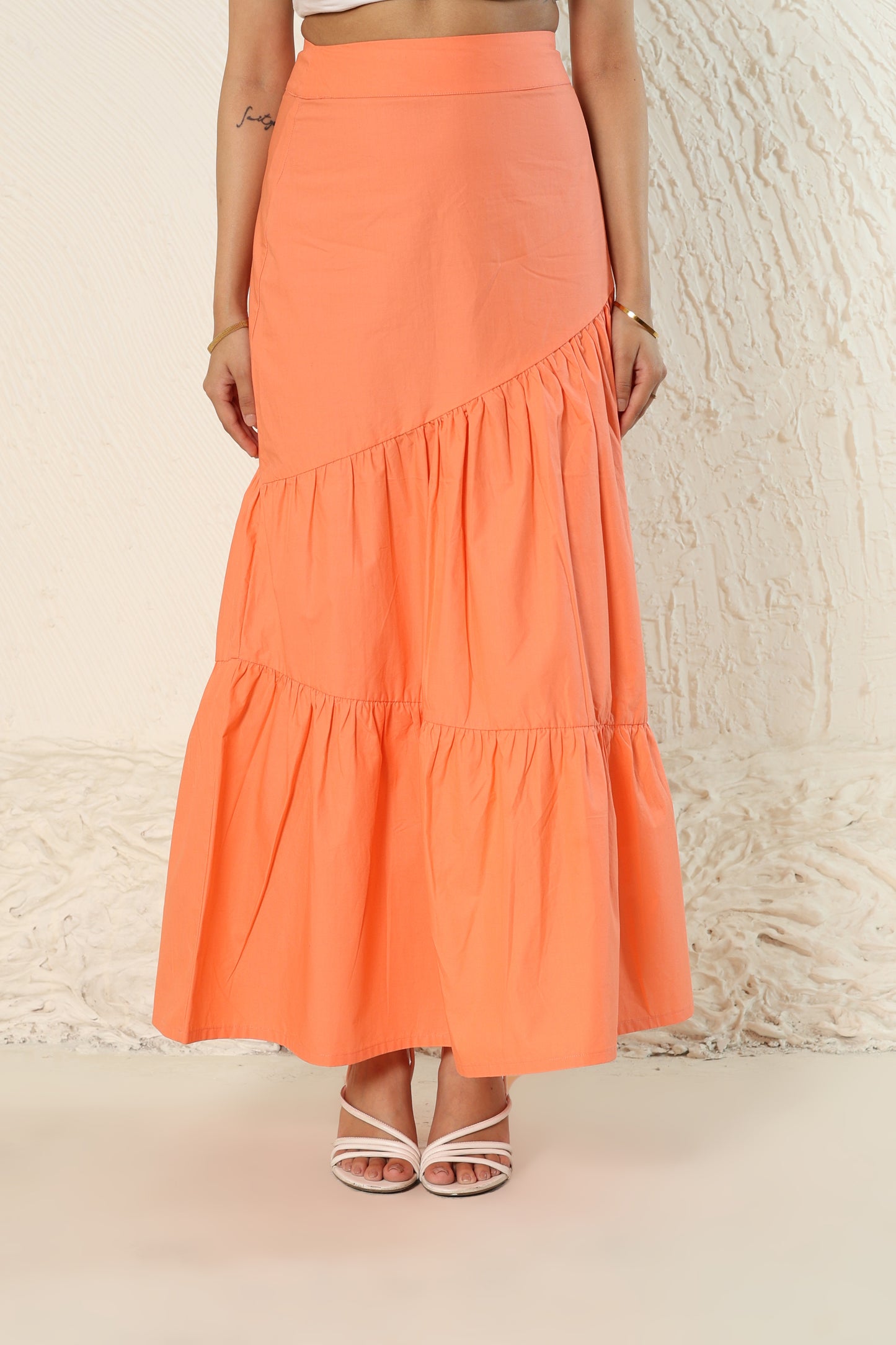 Person wearing an orange tiered skirt against a neutral background