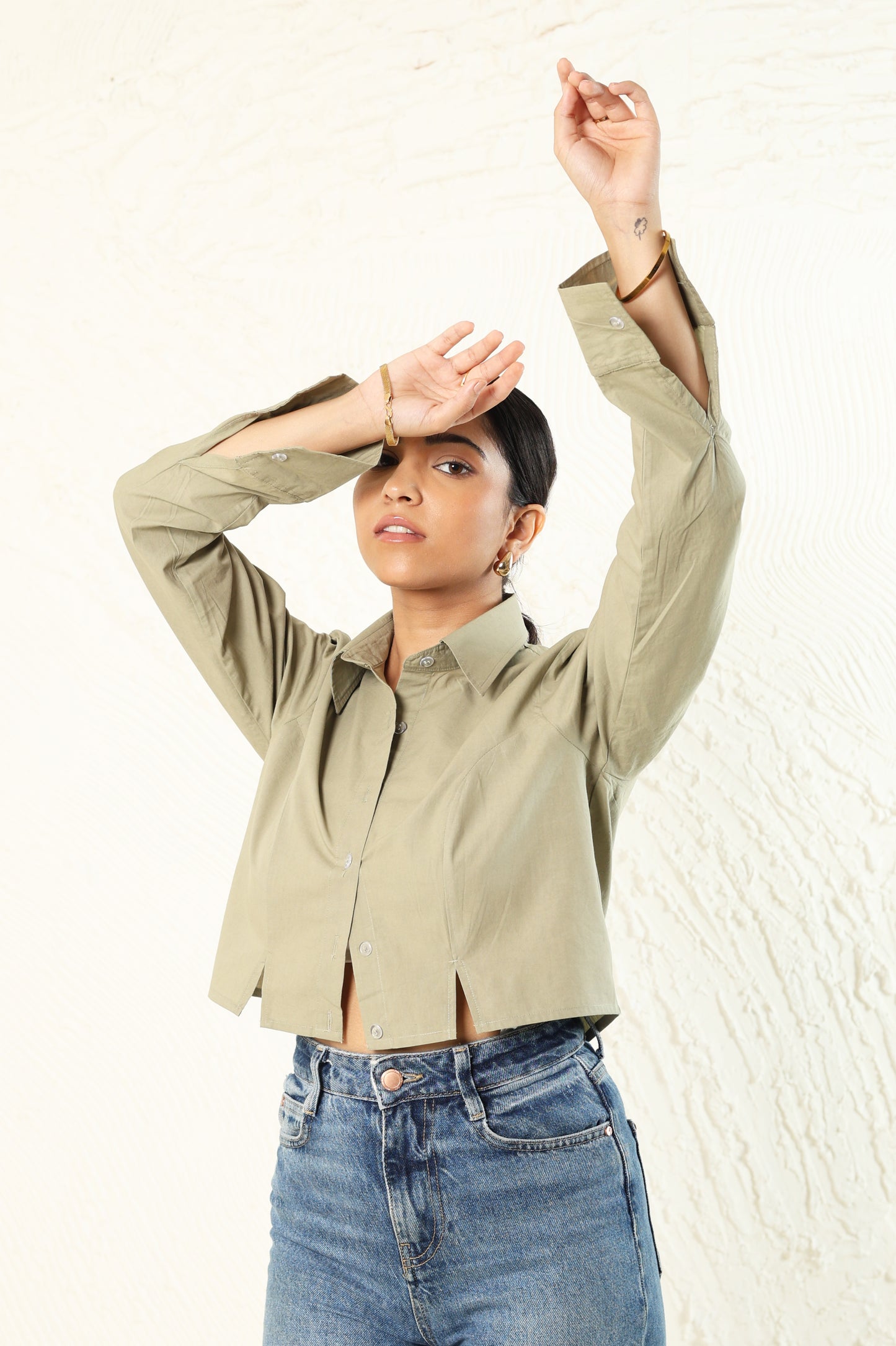 Person wearing a beige jacket and blue jeans against a white background