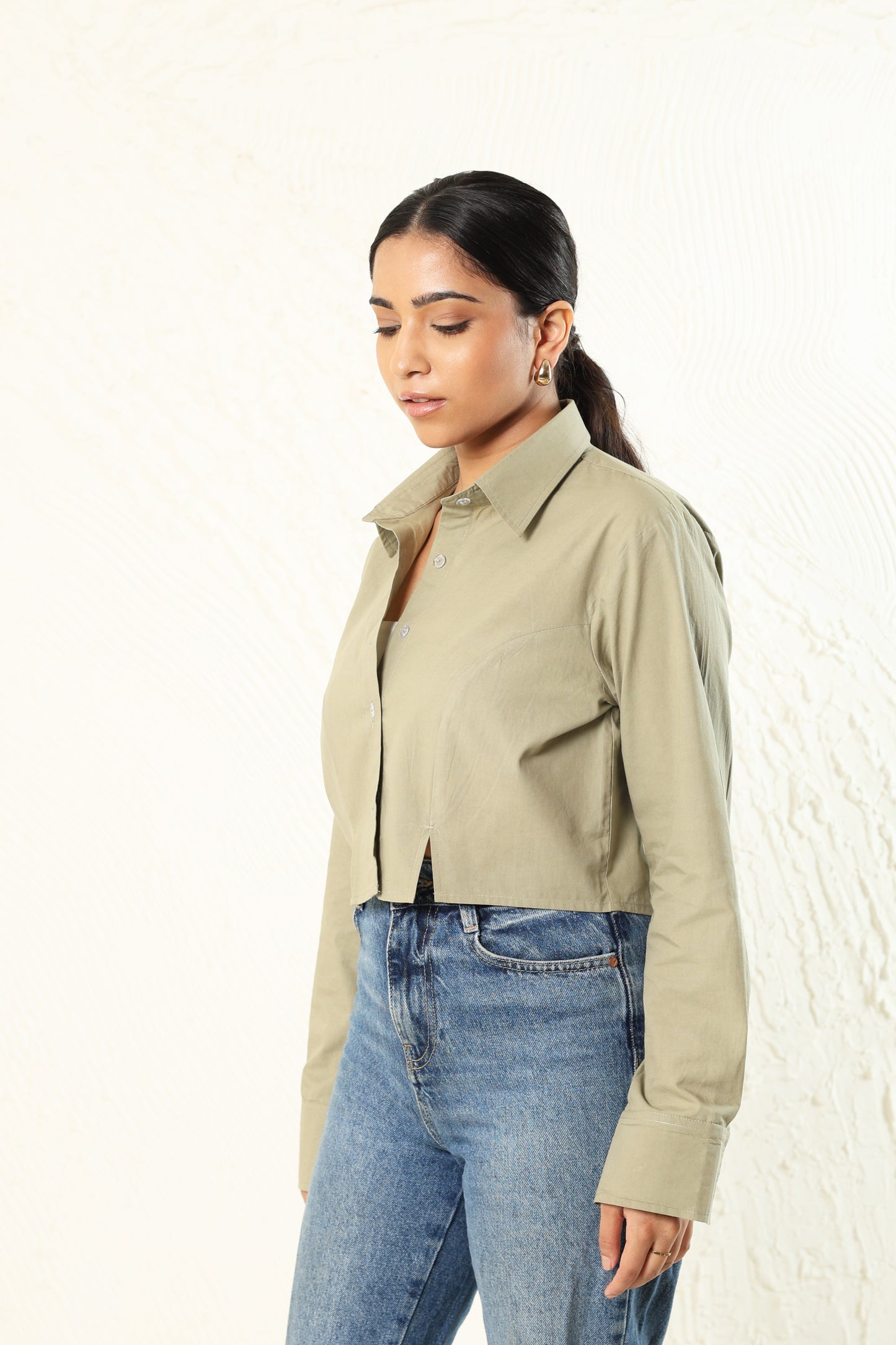 Woman wearing a beige jacket and blue jeans against a white background