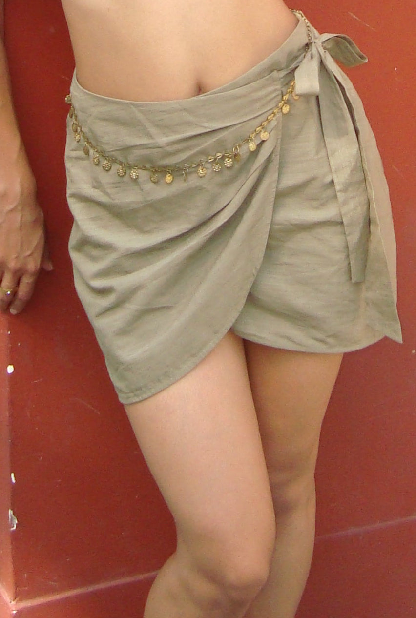 Person wearing a green skirt with gold embellishments against a red background