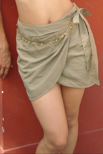 Person wearing a green skirt with gold embellishments against a red background