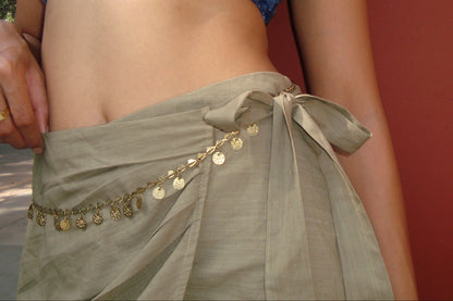 Green skirt with gold accents against a red wall.