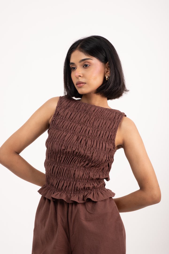Woman wearing a brown sleeveless top and pants on a white background