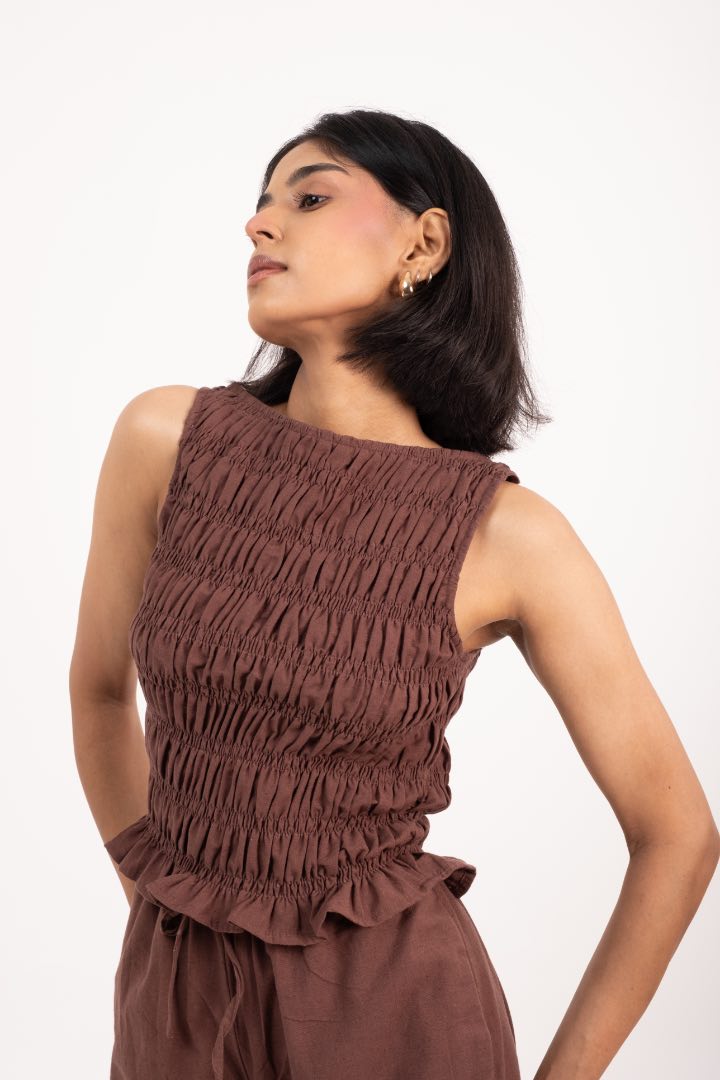 Woman wearing a brown textured top and pants on a white background