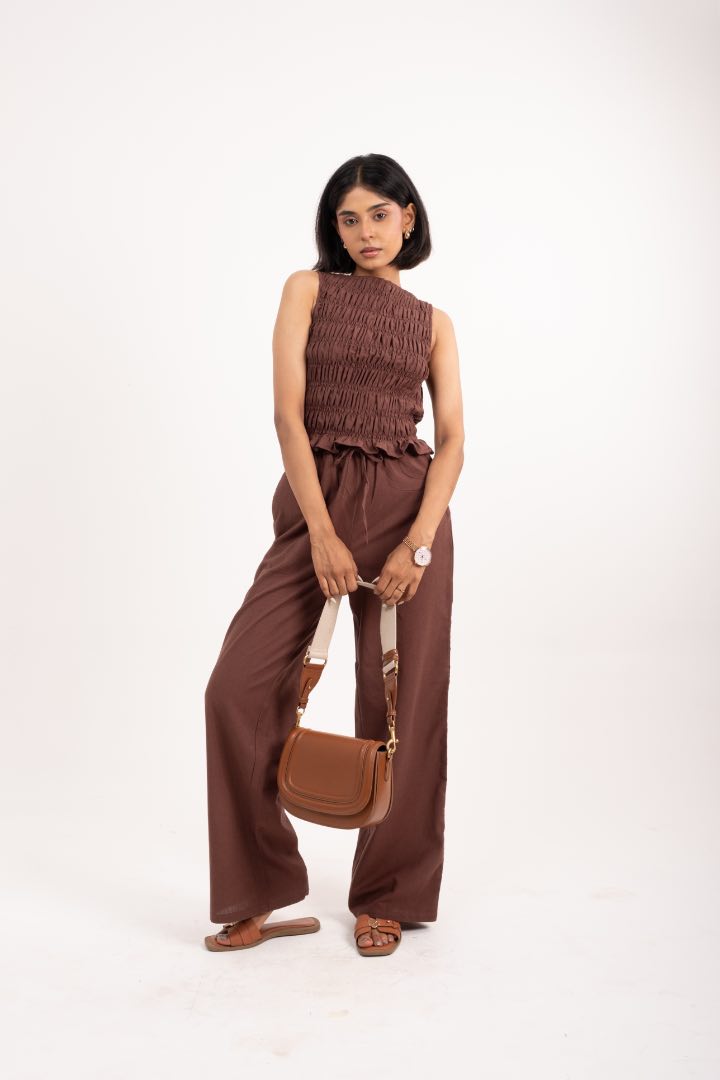 Woman wearing a brown outfit with a matching handbag on a white background