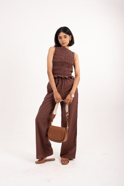 Woman wearing a brown outfit with a matching handbag on a white background