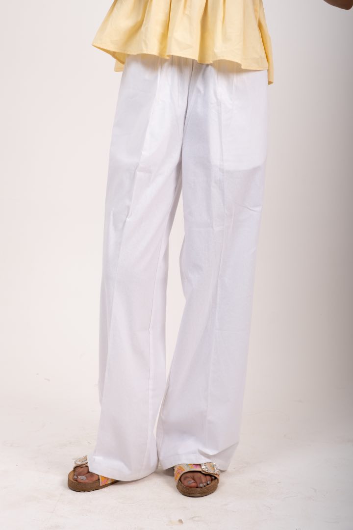 Person wearing a yellow top and white pants on a plain background
